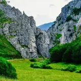 Majestuosas rocas flanquean un valle verde, donde la **cascada de Mazobre** se esconde entre la vegetación exuberante.
