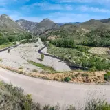 Paisaje montañoso con río y viñedos. La carretera serpentea, guiando hacia Arnedo.