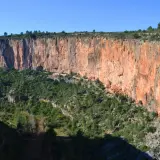 Impresionante cañón con paredes rojizas y vegetación verde. Los puentes colgantes de Chulilla se asoman entre la naturaleza.
