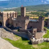 Imponente castillo de Javier, con su basílica anexa y torres defensivas, se alza majestuoso sobre un paisaje verde y montañoso.