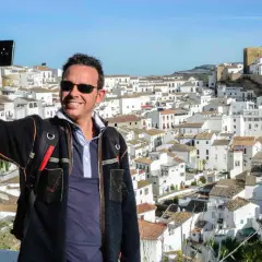 Hombre sonriente se toma selfie con el pueblo blanco de Bornos al fondo. ¡Descubre cómo llegar a este pintoresco lugar!