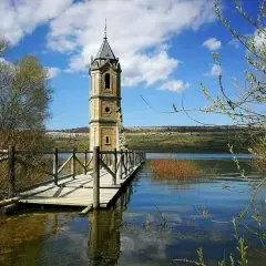 La **catedral de los peces**, una torre solitaria emerge del agua, conectada por un puente de madera.