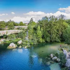 La cascada del peñón, con aguas cristalinas y rodeada de exuberante vegetación, invita a refrescarse. Personas disfrutan del baño y la naturaleza.