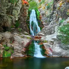 Cascada del Purgatorio, una joya natural en la ruta. Agua cayendo entre rocas y vegetación exuberante.