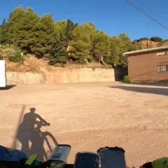 Encuentra la bogarra en este camino de tierra, con una caravana y un edificio de ladrillo al fondo.