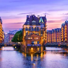 Canal de Hamburgo al atardecer, perfecto para saber donde ir en el puente de diciembre. Edificios de ladrillo iluminados reflejándose en el agua.
