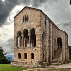 La iglesia Santa María del Naranco, joya prerrománica asturiana, se alza majestuosa bajo un cielo nublado.