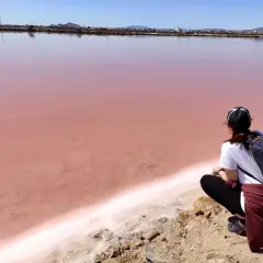Persona observa el agua rosada de las salinas de San Pedro, un paisaje único.