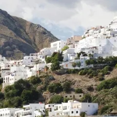 Casas blancas se aferran a una ladera montañosa, un laberinto de calles que invitan a descubrir Mojácar. ¿Cómo llegar? Sigue el sol.