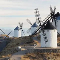Los icónicos molinos de Consuegra se alzan sobre una colina, sus aspas recortadas contra un cielo nublado.