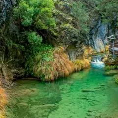 Un sendero de madera serpentea junto a un río de aguas cristalinas en la cerrada de Elías.