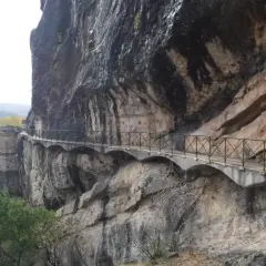 Un pontón de la oliva se aferra a un acantilado rocoso, con un camino bordeado de barandillas que serpentea a lo largo.