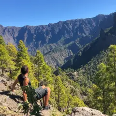 Hombre sentado en la ladera, contemplando el imponente paisaje montañoso del **cubo de la galga**.