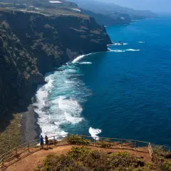 Pareja admira la playa de nogales, una costa volcánica de arena negra bañada por el azul intenso del océano.