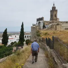 Hombre camina por sendero hacia iglesia en Medina Sidonia. Descubre cómo llegar a este pueblo blanco andaluz.
