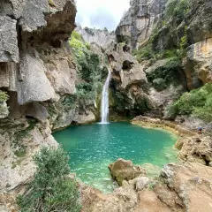 La cascada de la calavera cae en una poza de agua turquesa, rodeada de rocas y vegetación exuberante.