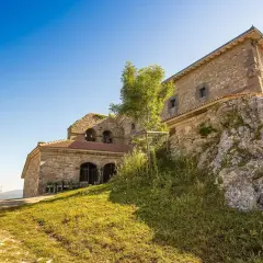 Antiguo santuario de oro en la cima de una colina rocosa, con un cielo azul brillante.
