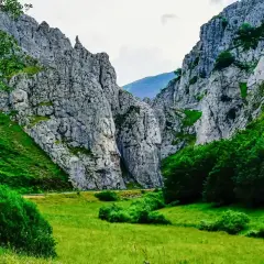 Majestuosas rocas flanquean un valle verde, donde la **cascada de Mazobre** se esconde entre la vegetación exuberante.