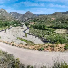 Paisaje montañoso con río y viñedos. La carretera serpentea, guiando hacia Arnedo.