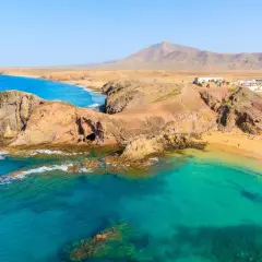 Aguas turquesas y arena dorada en una de las mejores playas de Lanzarote. Un paisaje volcánico se funde con el océano Atlántico.