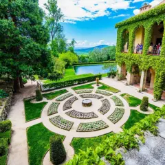 Jardín renacentista con estanque y edificio cubierto de hiedra, evocando la serenidad de los Cuacos de Yuste.
