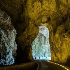 Un camino serpentea a través de las impresionantes cuevas del agua, iluminado por luces doradas que resaltan las formaciones rocosas.