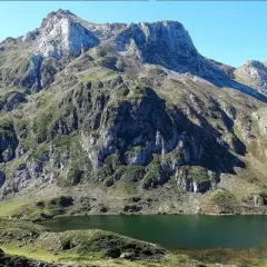 Majestuoso lago en la ruta Lagos de Saliencia, rodeado de imponentes montañas rocosas y vegetación verde.