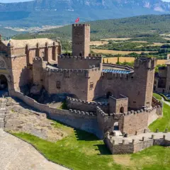 Imponente castillo de Javier, con su basílica anexa y torres defensivas, se alza majestuoso sobre un paisaje verde y montañoso.