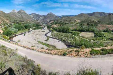 Paisaje montañoso con río y viñedos. La carretera serpentea, guiando hacia Arnedo.