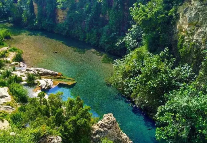 Un río de aguas cristalinas serpentea entre acantilados cubiertos de vegetación exuberante. Los lagos de Anna, un paraíso natural de tonos turquesa y verdes intensos.