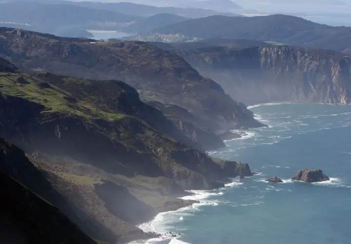 Majestuosos acantilados de San Andrés de Teixido se alzan sobre el mar Cantábrico, con verdes laderas y el azul profundo del océano.