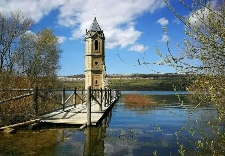 La **catedral de los peces**, una torre solitaria emerge del agua, conectada por un puente de madera.