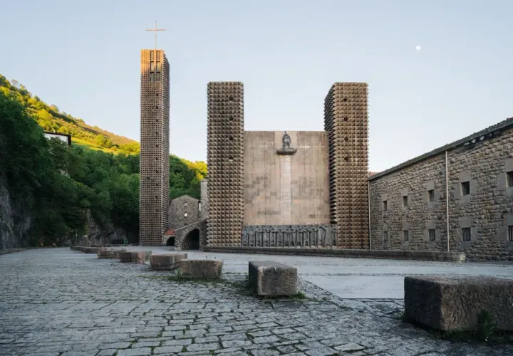 Santuario de Arantzazu con su torre alta, fachada de piedra y esculturas.