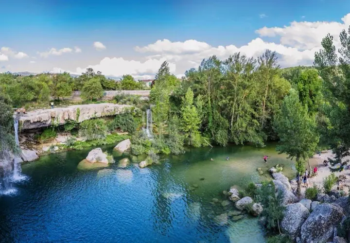 La cascada del peñón, con aguas cristalinas y rodeada de exuberante vegetación, invita a refrescarse. Personas disfrutan del baño y la naturaleza.