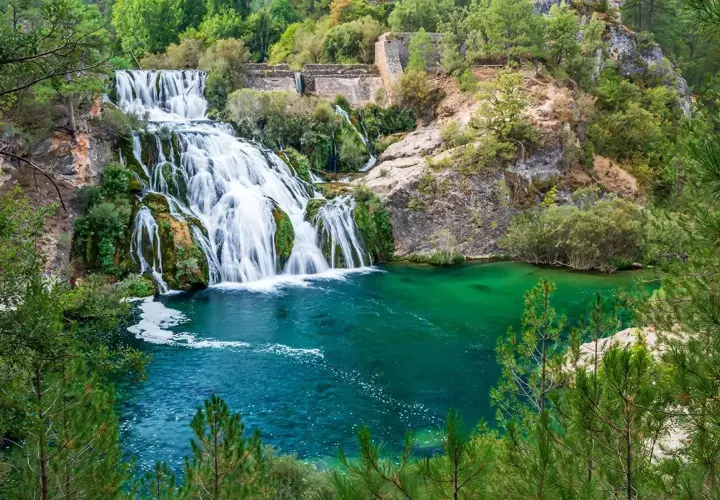 Cascada y laguna de Uña, con aguas turquesas y vegetación exuberante.