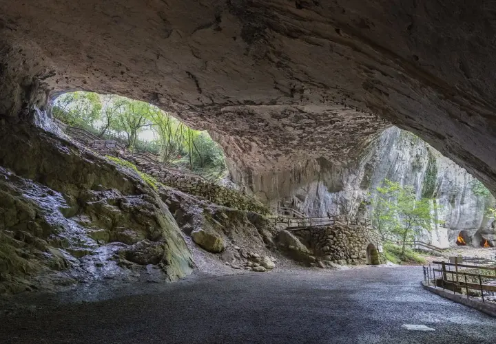 Interior de una cueva con escaleras de madera y piedra que llevan al exterior. Para saber zugarramurdi como llegar, sigue el camino.