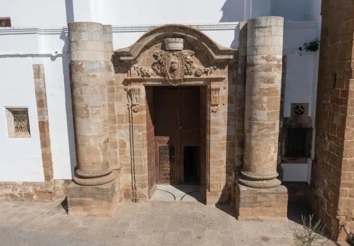 Impresionante portal de piedra con detalles ornamentales, flanqueado por columnas. Parece la entrada a una capilla Sixtina extremeña, invitando a descubrir su interior.