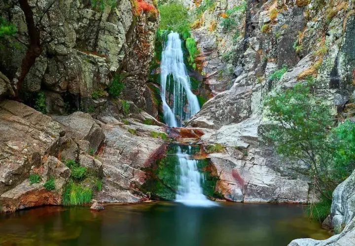 Cascada del Purgatorio, una joya natural en la ruta. Agua cayendo entre rocas y vegetación exuberante.