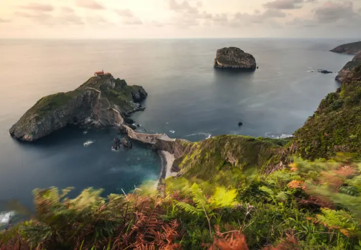 Las escaleras de San Juan de Gaztelugatxe serpentean hacia una ermita en una isla rocosa, rodeada por el mar Cantábrico.