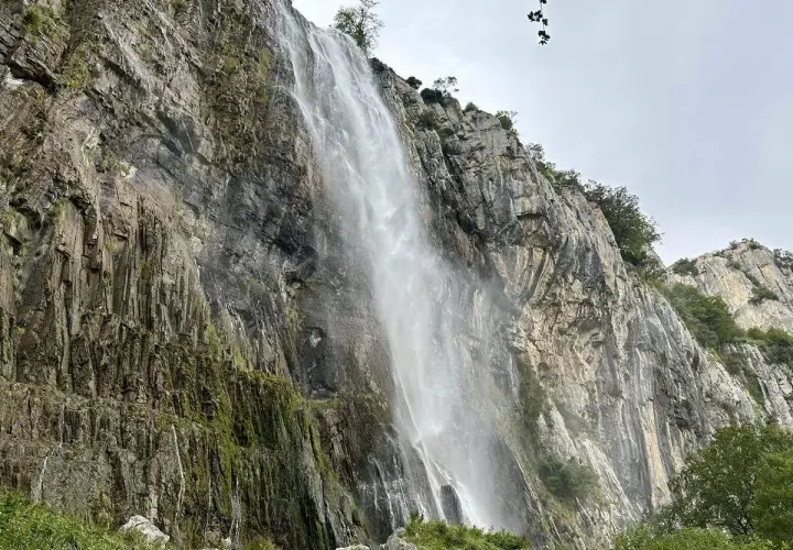 Majestuosa cascada del Ason cayendo por un imponente acantilado rocoso cubierto de vegetación.
