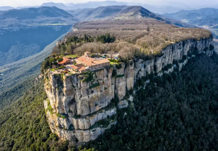 El santuari del Far se alza majestuoso sobre un acantilado, rodeado de montañas y bosques.