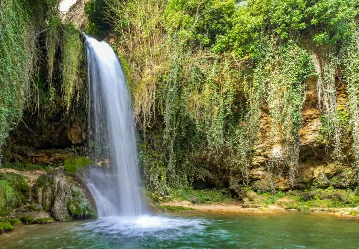 Cascadas en Burgos, un rincón verde y exuberante donde el agua cae sobre rocas cubiertas de musgo y enredaderas.