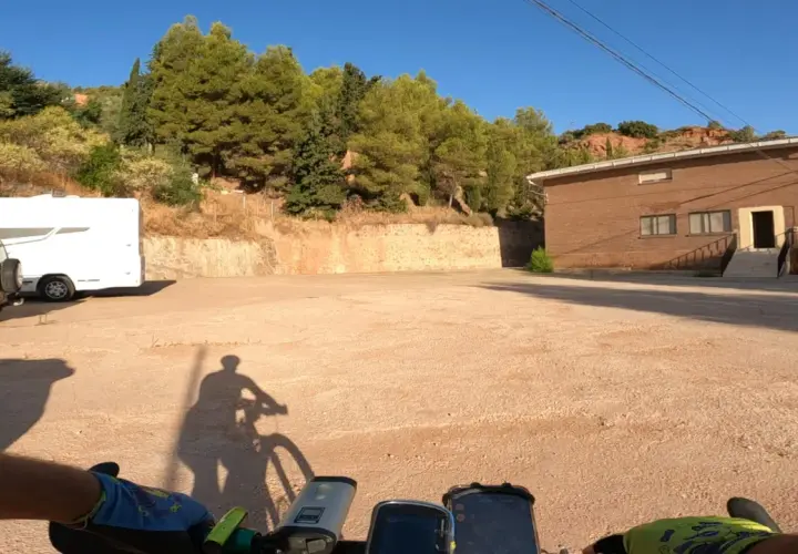 Encuentra la bogarra en este camino de tierra, con una caravana y un edificio de ladrillo al fondo.