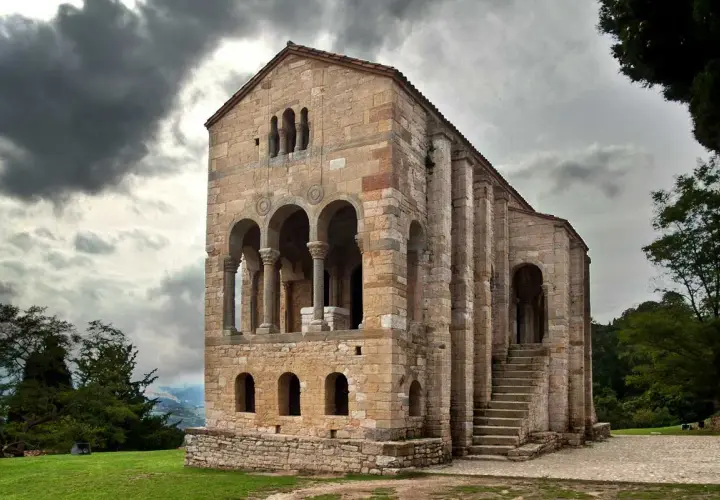La iglesia Santa María del Naranco, joya prerrománica asturiana, se alza majestuosa bajo un cielo nublado.
