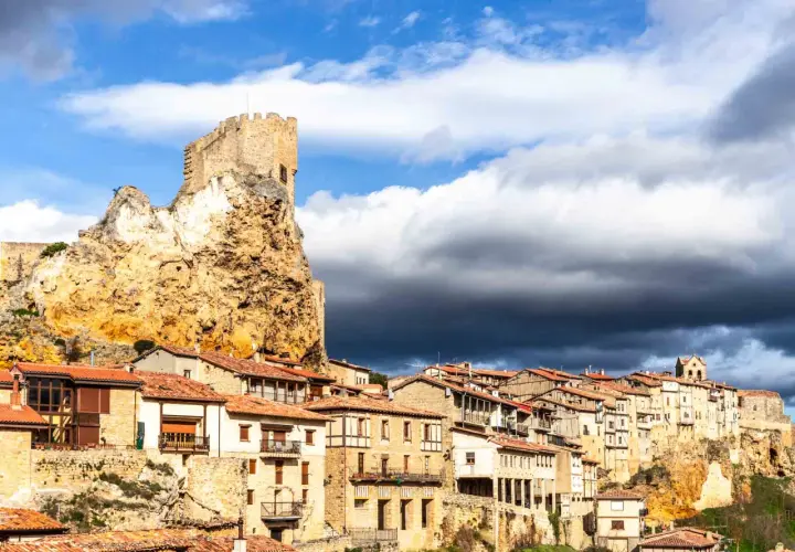 Pueblo medieval en un risco rocoso, con un castillo en la cima. Las casas se aferran a la ladera. Frias como llegar, un destino histórico.