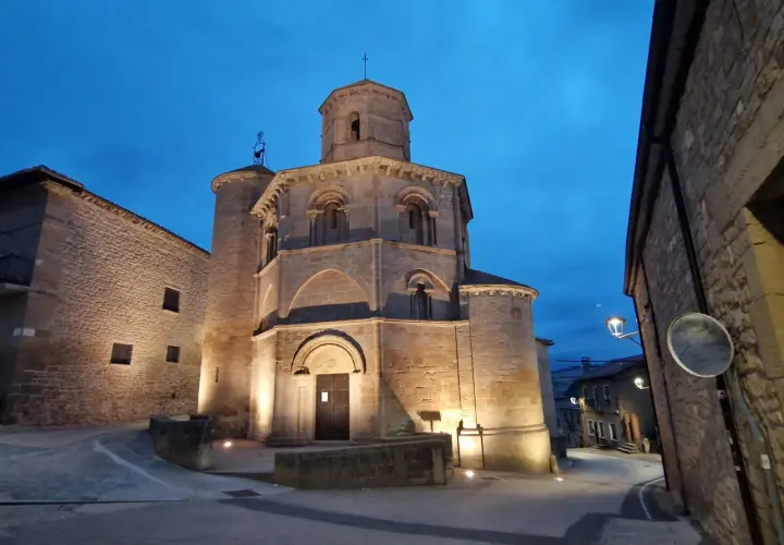 Las torres del río iluminadas al anochecer, con una iglesia románica y calles empedradas.