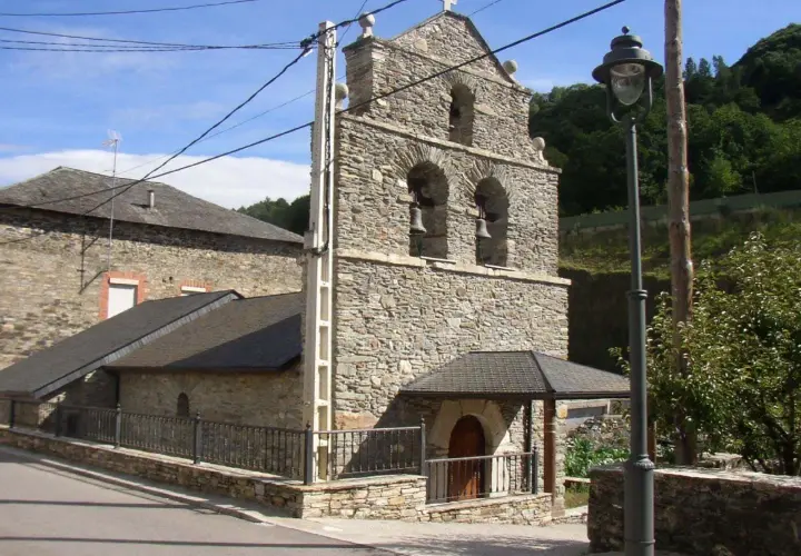 Iglesia de piedra en La Portela de Valcarce, con campanario de dos arcos y campanas. Un farol ilumina la entrada.