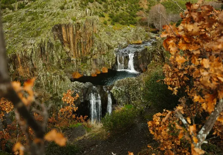 Cascada del Aljibe en otoño, con hojas doradas y rocas cubiertas de musgo.