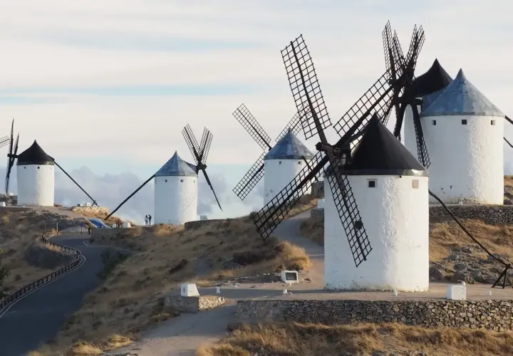Los icónicos molinos de Consuegra se alzan sobre una colina, sus aspas recortadas contra un cielo nublado.