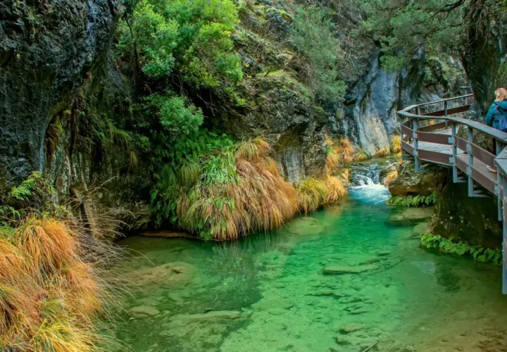 Un sendero de madera serpentea junto a un río de aguas cristalinas en la cerrada de Elías.